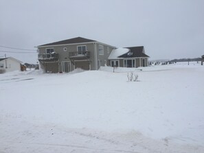 A two-story house with a balcony, surrounded by snow.