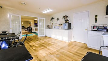 Uma cozinha espaçosa com armários brancos, piso de madeira e um espaço de refeições com cadeiras pretas.