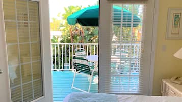A room with a bed, a door leading to a balcony, and a table with chairs outside.
