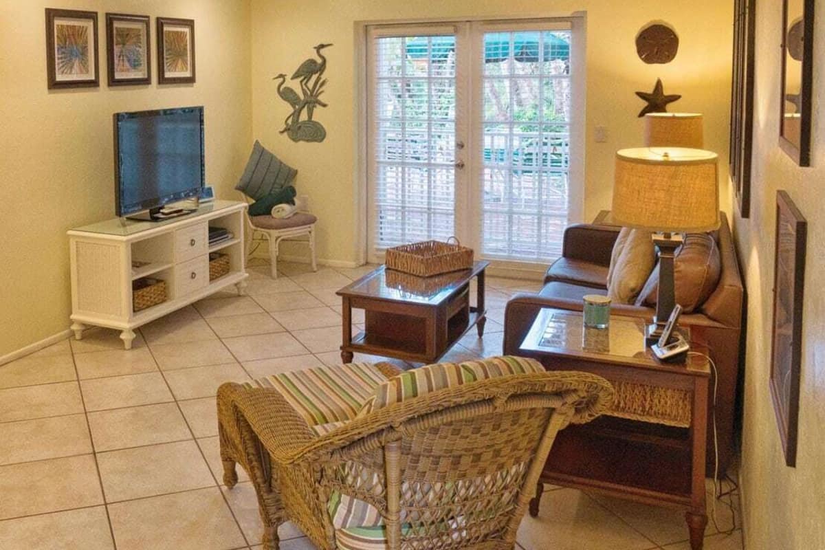 A living room with a television, wicker furniture, a sofa, a coffee table, and a lamp.