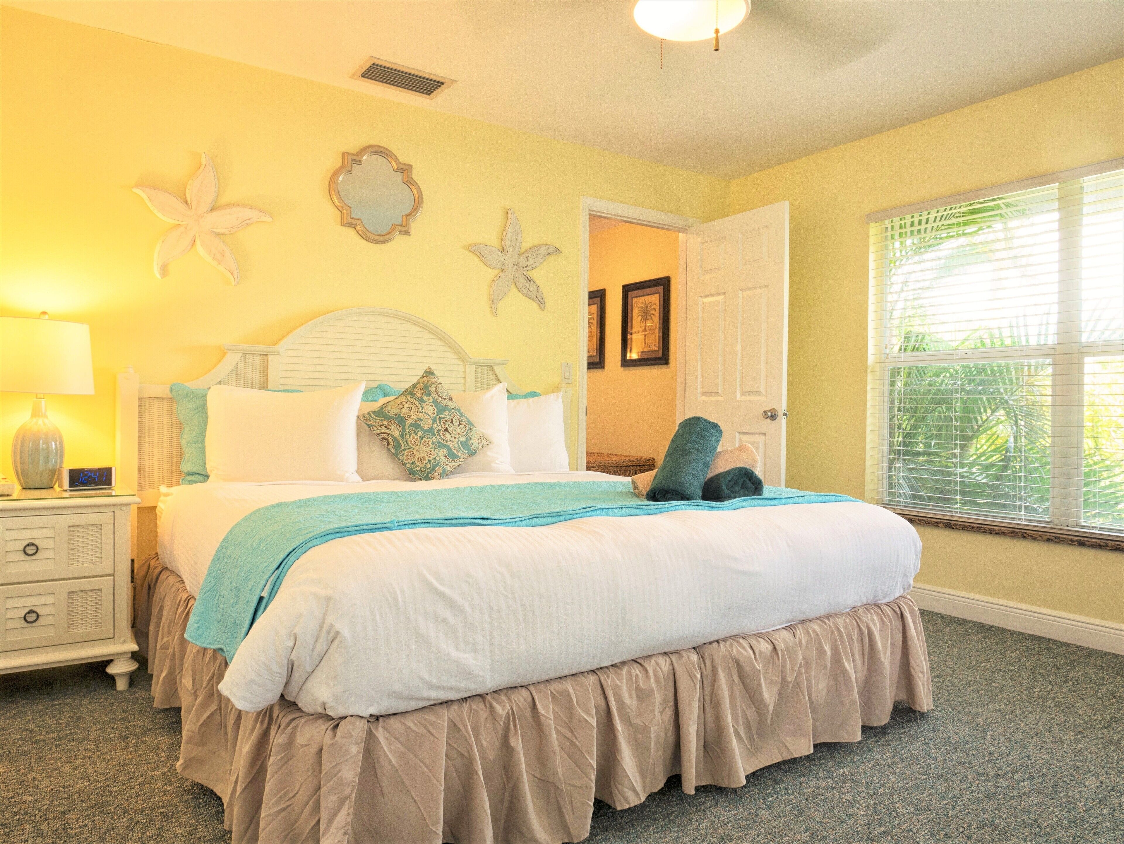 A bedroom with a bed, a nightstand, a lamp, and a window with blinds.