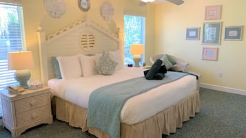 Une chambre bien rangée, avec un lit, des tables de chevet, un ventilateur de plafond et des décorations murales.