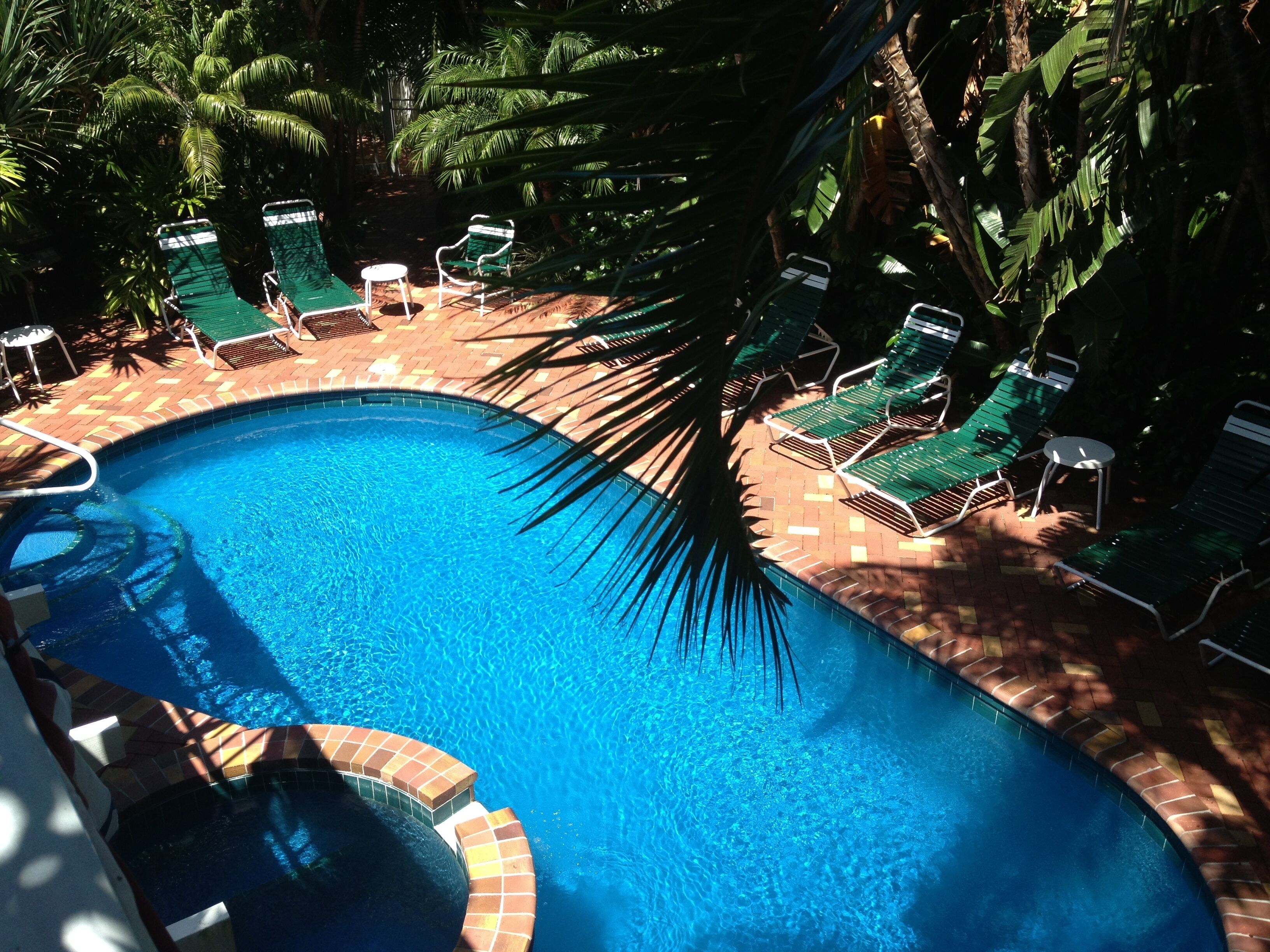 Une piscine bordée de briques et dotée d’une terrasse carrelée.
