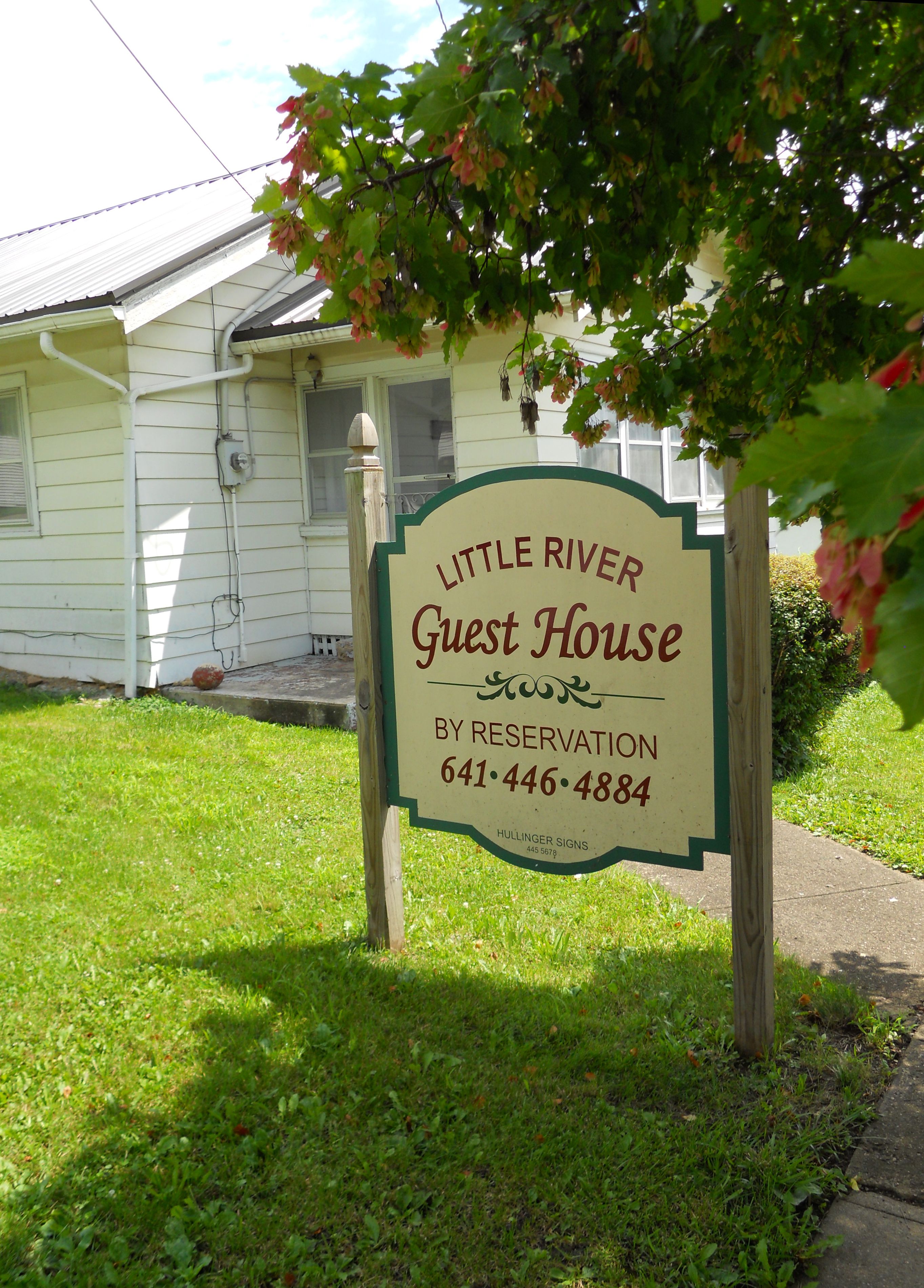 A sign for the Little River Guest House by reservation with a contact number.