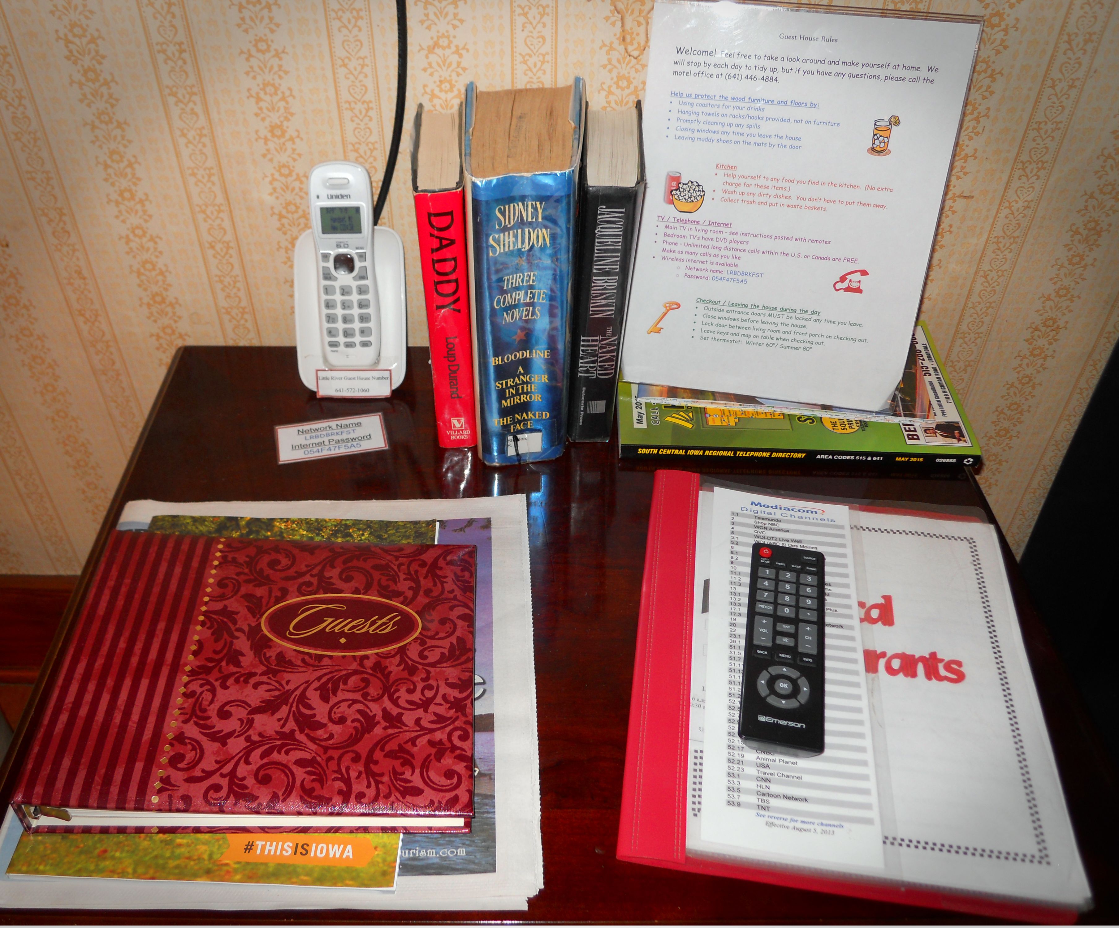 Un bureau avec un téléphone, des livres, une télécommande et un annuaire imprimé.