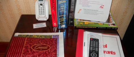 Un bureau avec un téléphone, des livres, une télécommande et un annuaire imprimé.