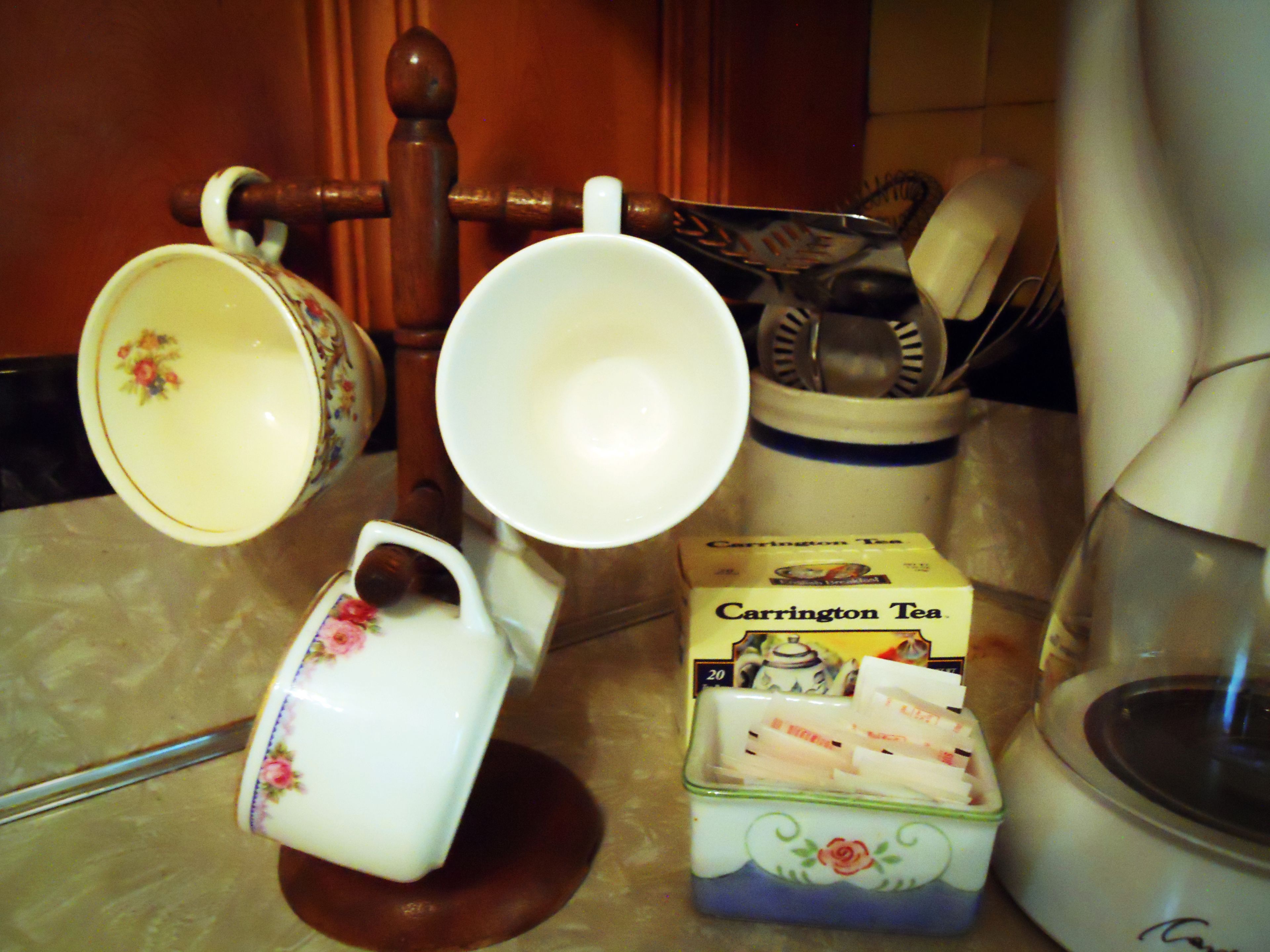 Una encimera de cocina con una caja de té, una cafetera y un hervidor.