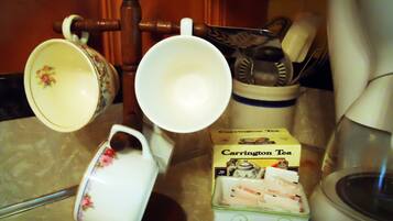 Una encimera de cocina con una caja de té, una cafetera y un hervidor.