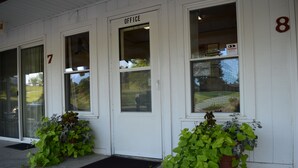 A building with numbered doors, including an office labeled door, and potted plants in front. - Little River Inn Motel & Guest House (Leon)
