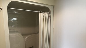 A bathroom with a bathtub, toilet, and a towel rack.