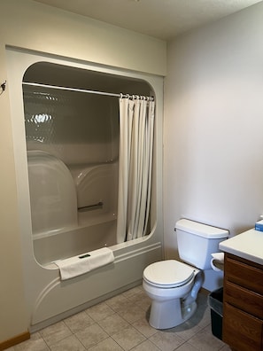 A bathroom with a bathtub, toilet, and a towel rack.