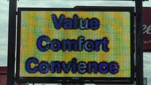 A sign for Budget Host Inn & Suites with a digital display below stating "Value Comfort Convenience".