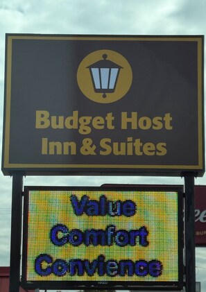 A sign for Budget Host Inn & Suites with a digital display below stating "Value Comfort Convenience".
