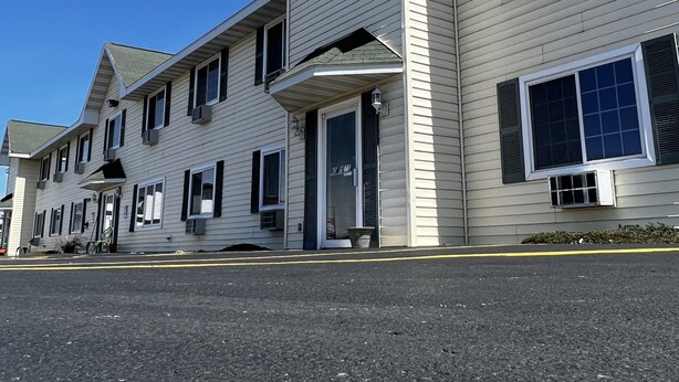 A row of two-story buildings with a flat roof, large windows, and a central entrance with a door and steps.