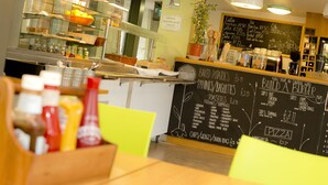 Un interior de restaurante con un menú en pizarra, botellas de condimentos y una vitrina.