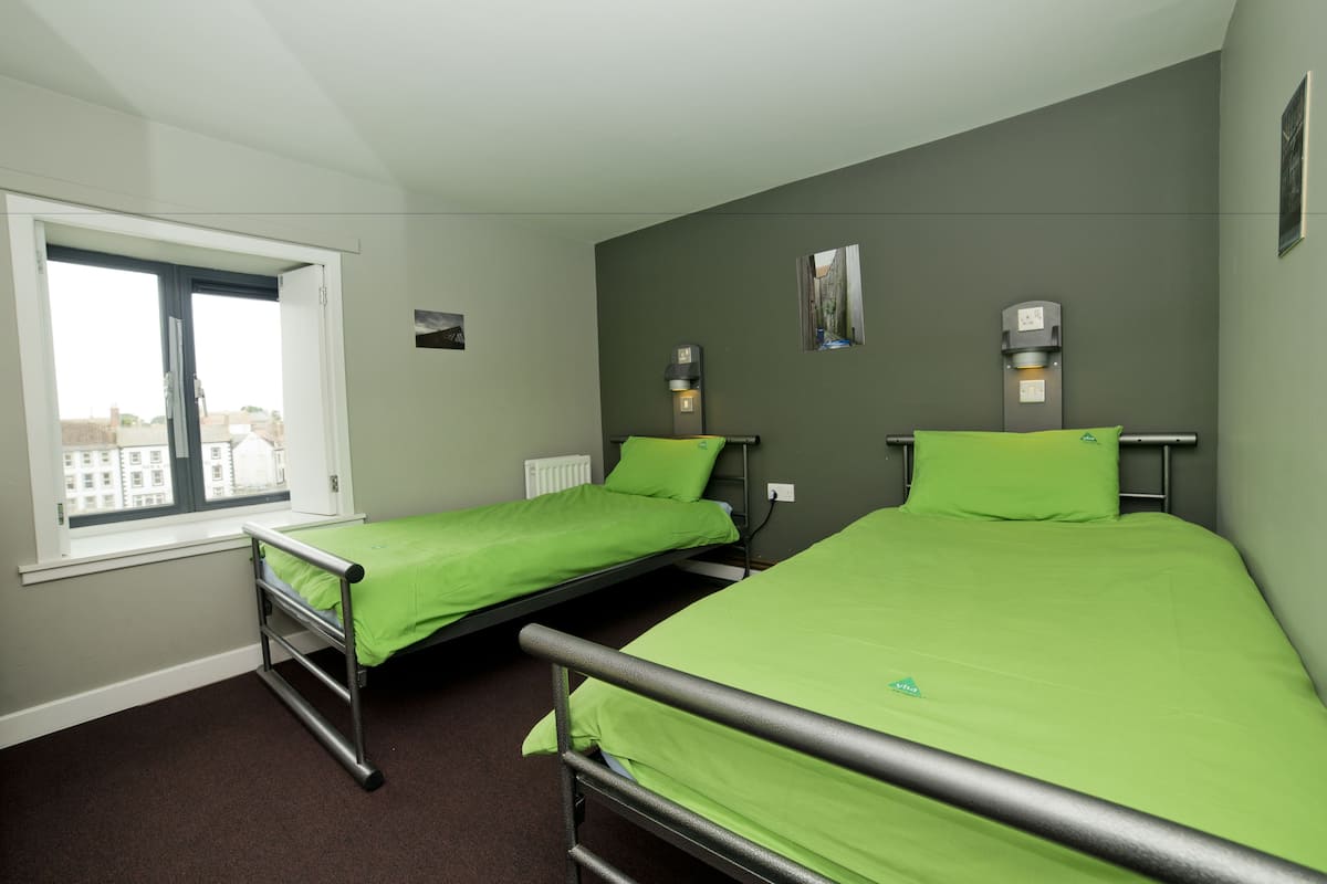 A room with two single beds, a window, and a radiator.