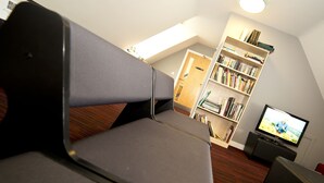 Una sala de estar moderna con un sofá, una estantería, un televisor y suelo de madera.