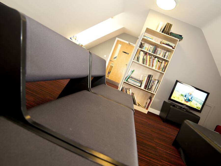 A modern living room with a sofa, a bookshelf, a television, and a wooden floor.