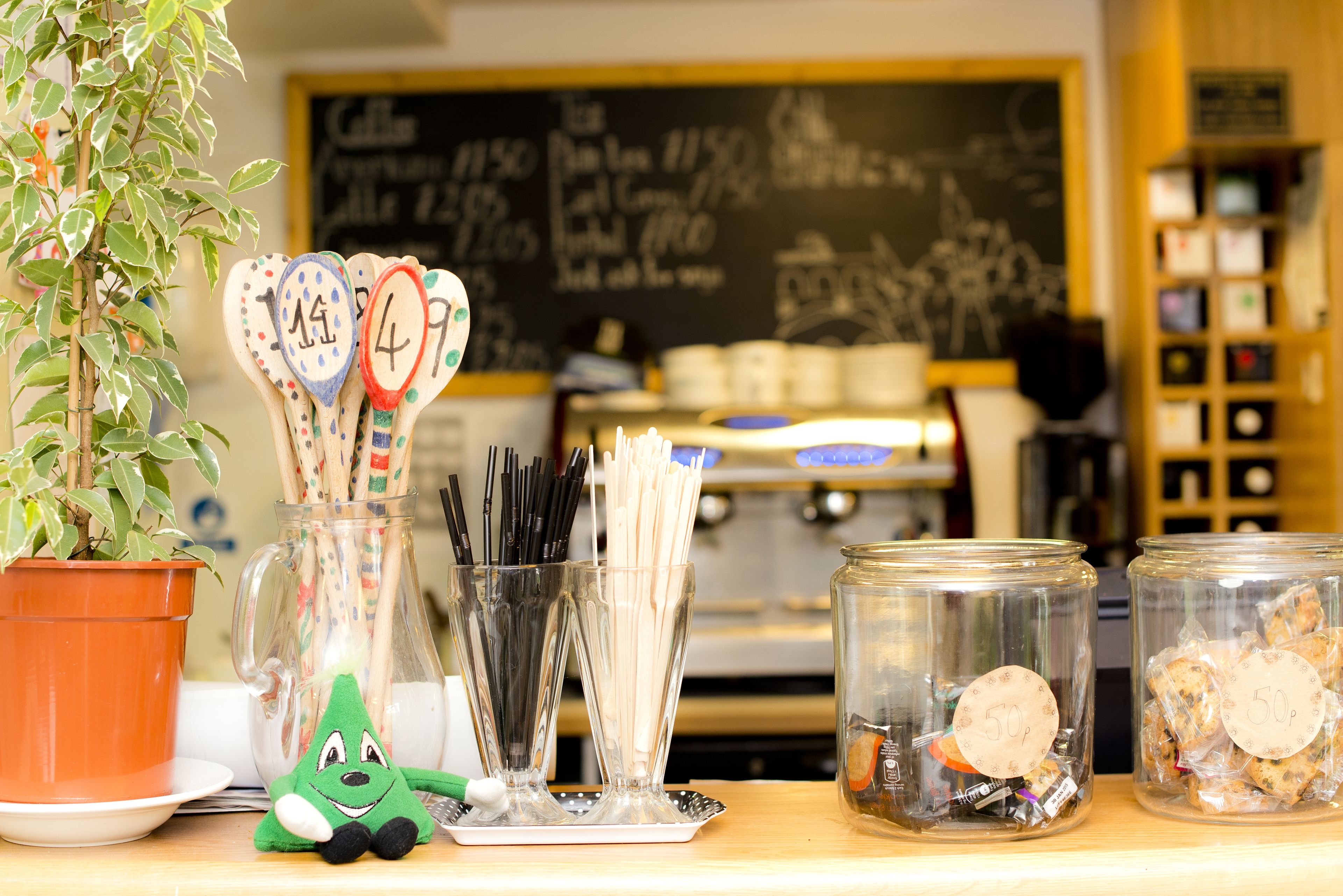 A kitchen counter with utensils, a potted plant, and jars labeled with prices.