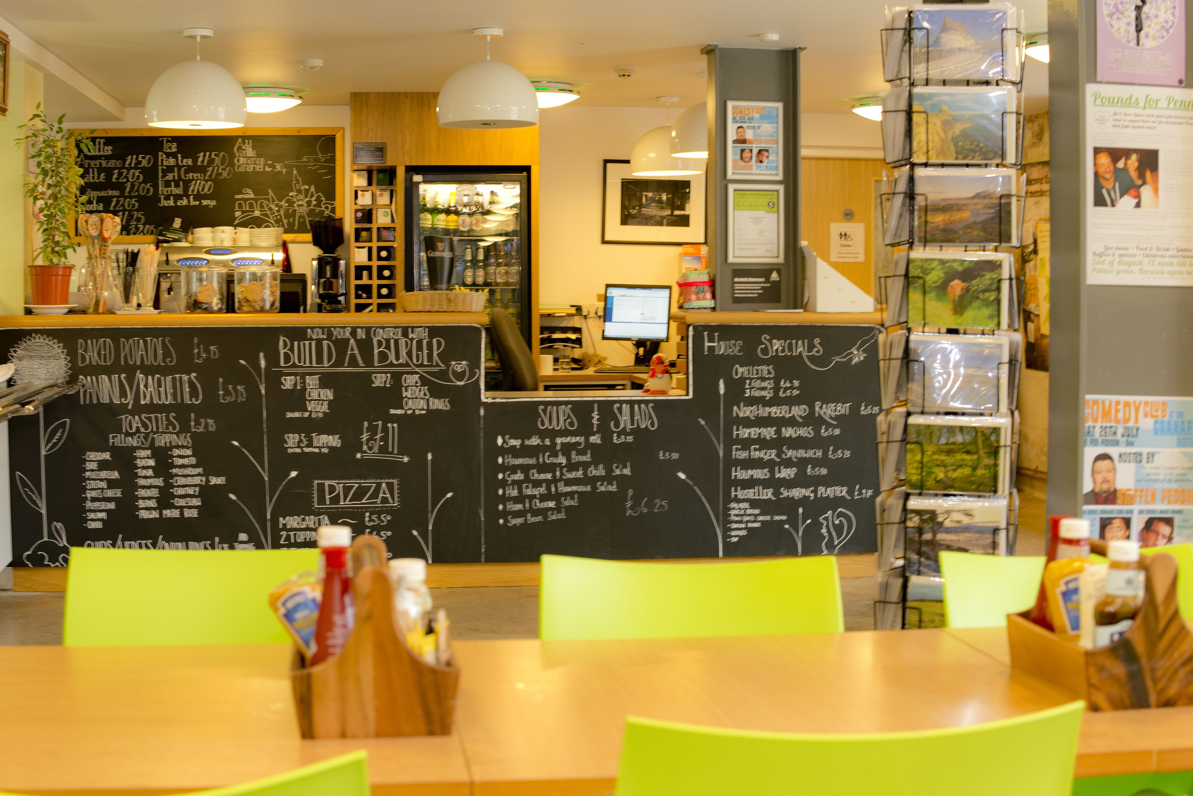 A restaurant interior with a chalkboard menu, a computer, and a display of postcards.