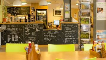 A restaurant interior with a chalkboard menu, a computer, and a display of postcards.