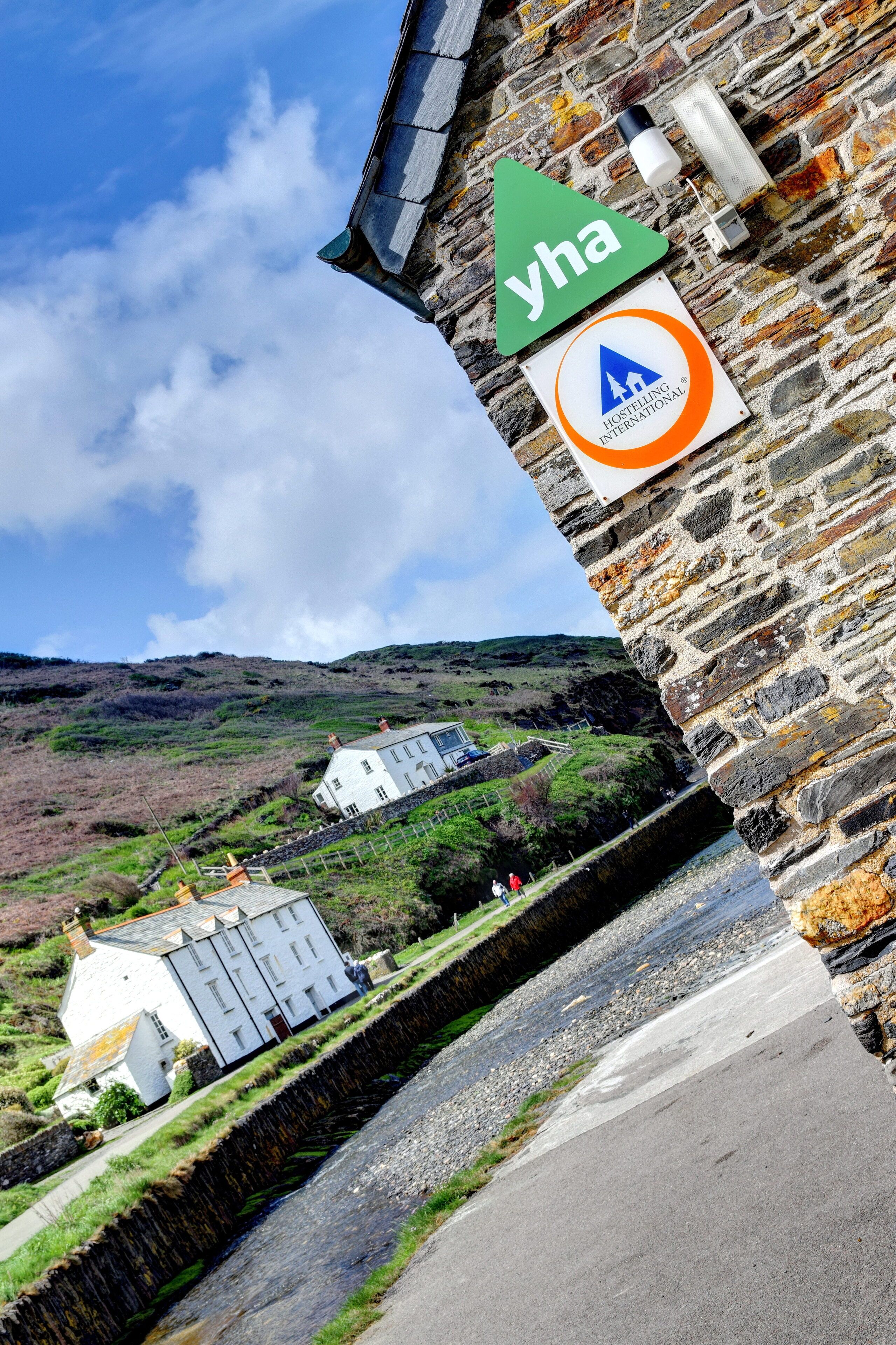 Ein Steinhaus mit einem Schild für 'yha' und dem Logo von 'Hostelling International'.