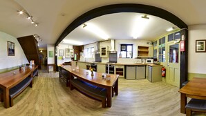 A spacious kitchen with wooden benches, a central island, and a view of the dining area.