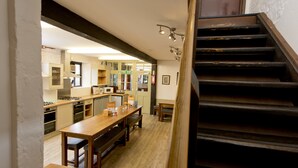 A kitchen with wooden countertops, a dining table, and a staircase leading to another level.