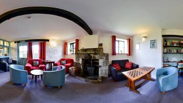 A cozy room with a fireplace, comfortable seating, and a chess table.