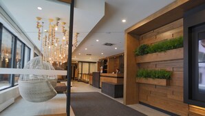 Een moderne receptiezone met een houten balie, een hanglamp en een groot raam dat natuurlijk licht binnenlaat.