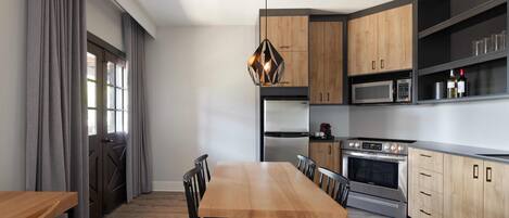 Una cocina moderna con una mesa de comedor de madera, sillas negras y electrodomésticos integrados.