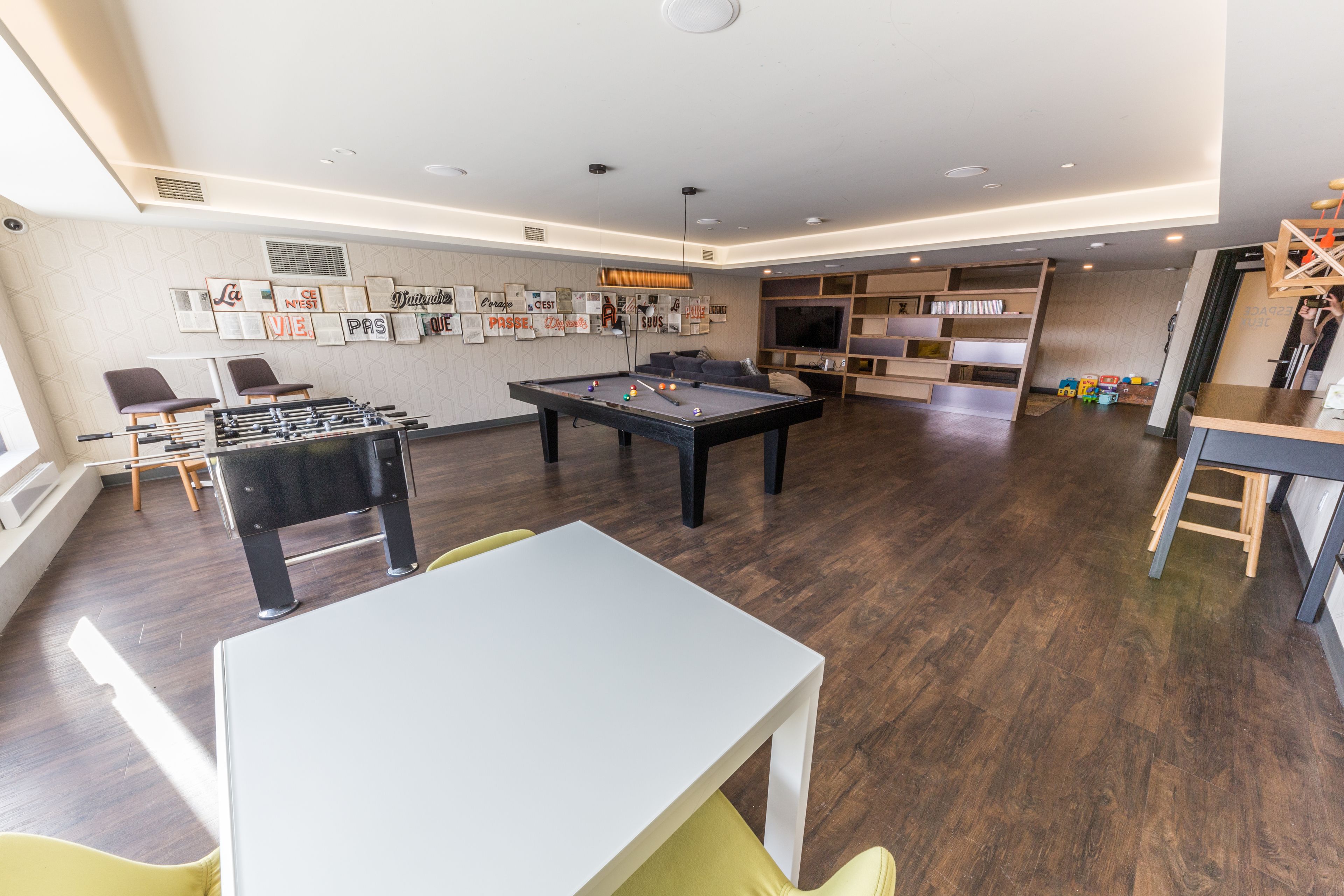 A modern living room with a pool table, foosball table, and comfortable seating.