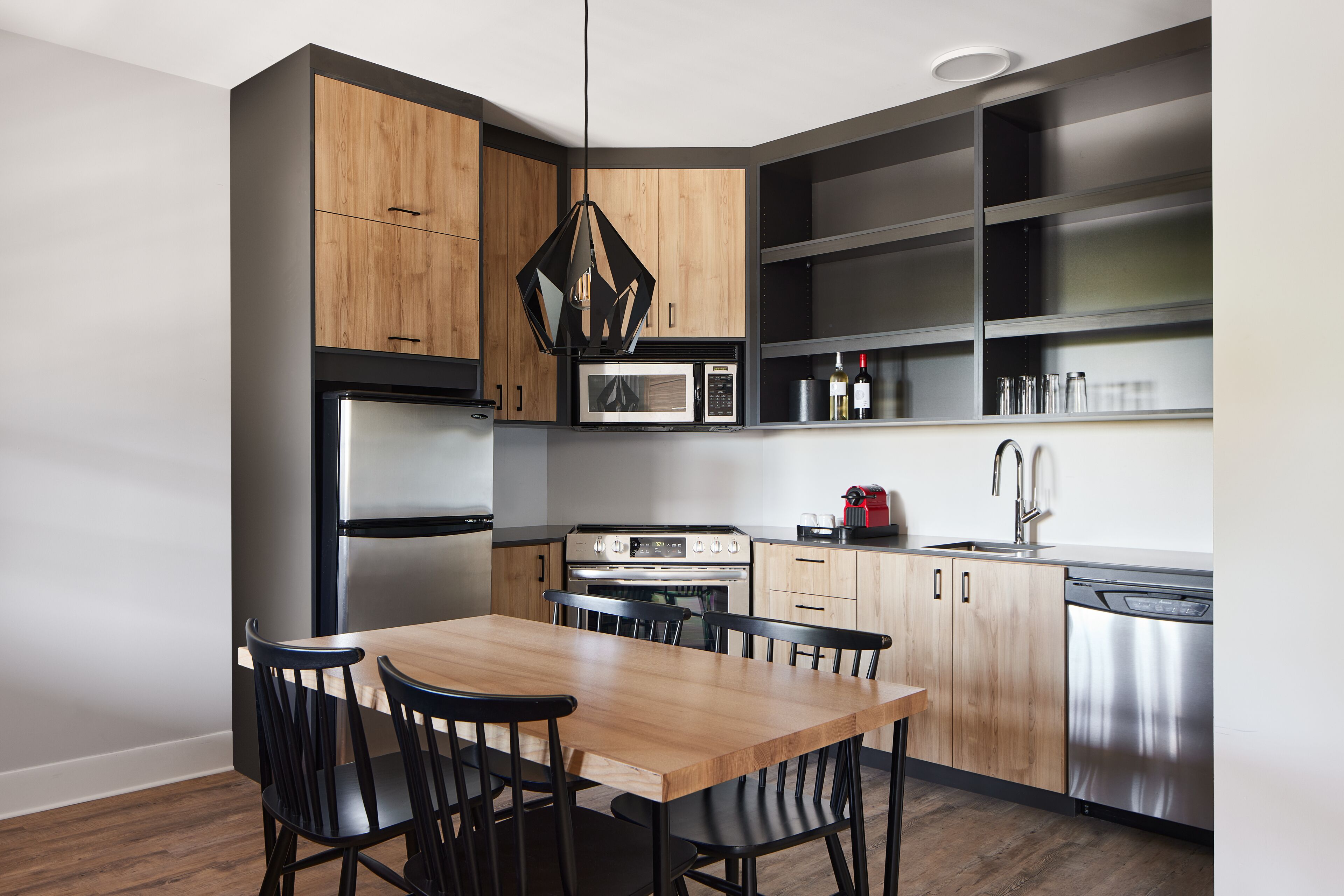 Una cocina moderna con armarios de madera, un refrigerador de acero inoxidable, un horno, un microondas y un lavavajillas.