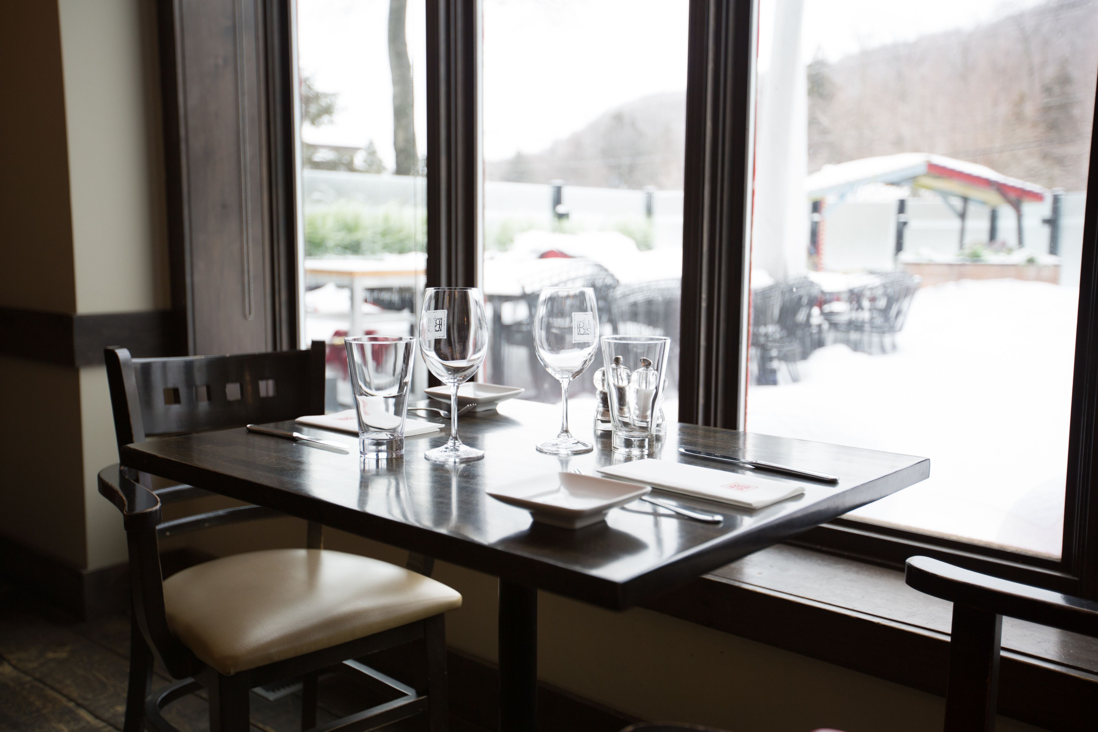 A dining table with chairs, clear glasses, and a menu.