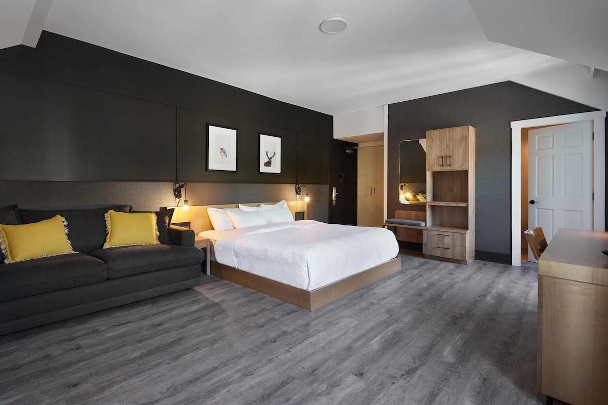 A modern bedroom with a large bed, a sofa, and a wardrobe.