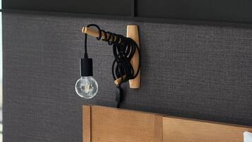 Un dormitorio moderno con cabecera de madera, mesita de noche y lámpara de pared.