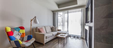 Een moderne woonkamer met een kleurrijke fauteuil, een bank, een salontafel en een open haard.