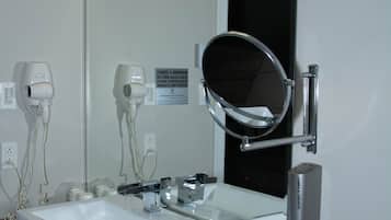 Un baño con dos lavamanos, un espejo grande y un secador de pelo en la pared.