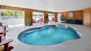 A pool area with a curved pool, wooden walls, and a ceiling fan.
