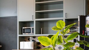 A modern kitchen with built-in appliances, a potted plant, and a wooden floor.