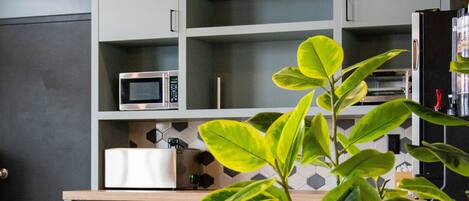 Uma cozinha moderna com eletrodomésticos embutidos, uma planta em vaso e piso de madeira.