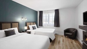 A hotel room with two beds, a TV, a chair, and a fireplace.