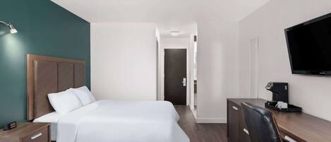 A hotel room with two beds, a desk, a chair, a TV, and a coffee machine.