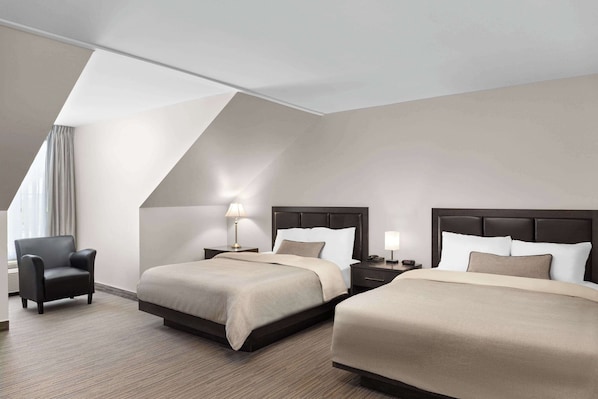 Habitación de hotel con dos camas, una silla y una lámpara.