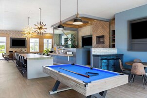 Cozinha moderna com mesa de bilhar, bar e área de refeições.
