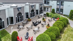 Une cour avec des espaces de détente en plein air, un espace couvert et un bâtiment doté de grandes fenêtres et d’un design moderne.