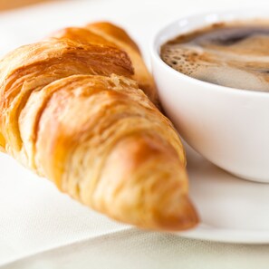 Un croissant y una taza de café sobre un plato blanco.