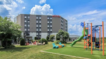 Experience a peaceful retreat with a flat roof and symmetrical facade, surrounded by a lush green space with a children's play area.