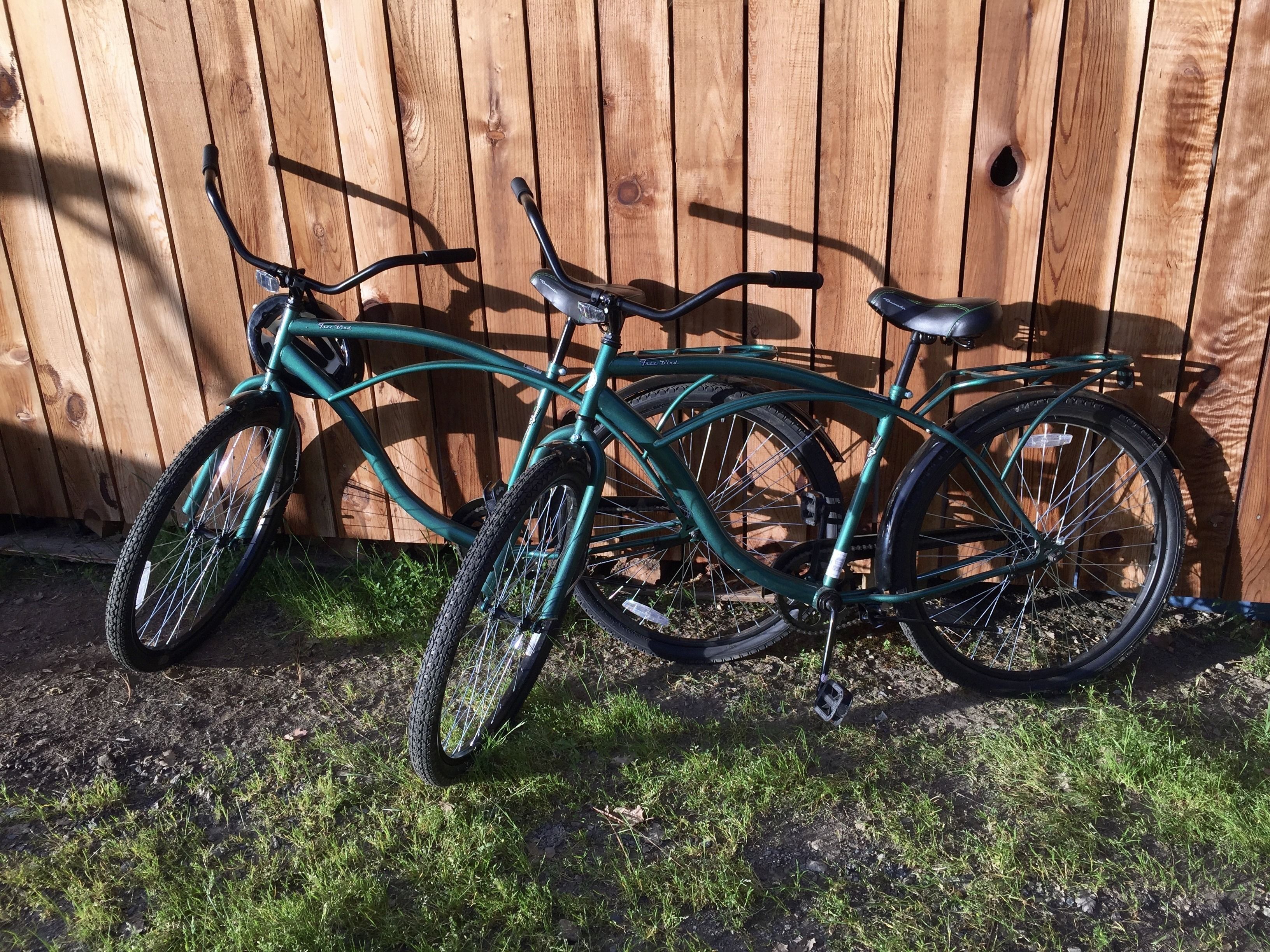 Two bicycles parked against a wooden fence.
