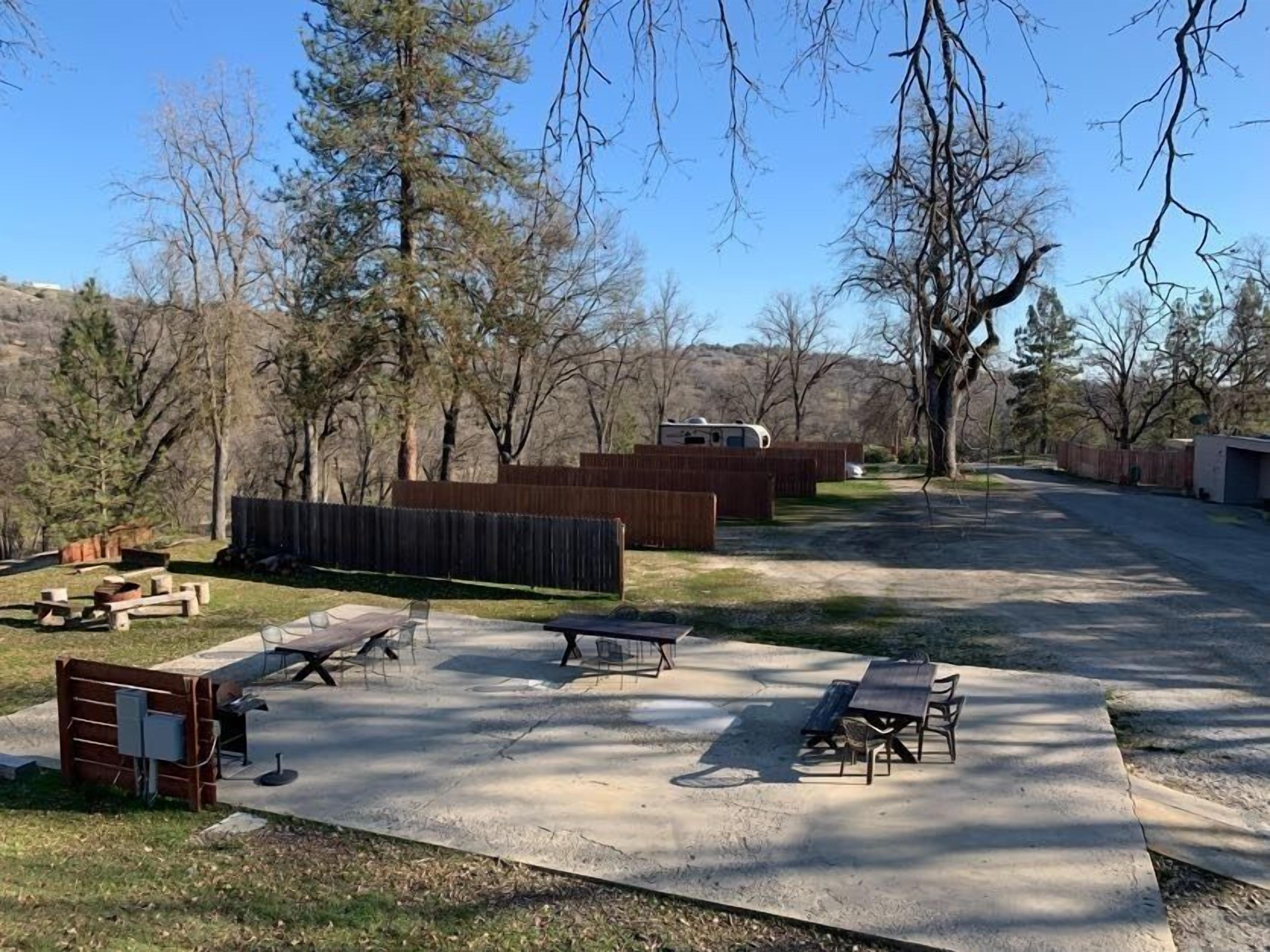 A campground with picnic tables, a covered picnic area, and a fenced play area.